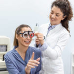 Optometrists changes lenses in trial frame to examine the vision of young woman patient vision at ophthalmology clinic, selective focus