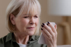 A retired woman struggling with her vision while looking at phone screen due to Myopia vision problems.