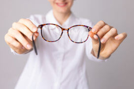 Ophthalmologist doctor pulling glasses for astigmatism treatment forward to a patient.